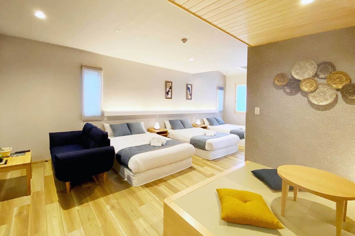 A hotel room with two beds, a sofa, a small table, and a decorative wall.