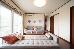 A room with a large window, a sofa, a coffee table, and a wall with decorative plates.