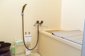 A bathroom with a bathtub, a shower, and a sink. There are toiletries on a shelf.