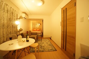 A cozy room with a dining table, chairs, a sofa, and a wooden door.