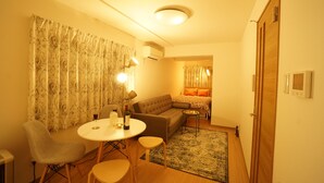 A cozy living room with a sofa, a dining table with chairs, and a small side table. - Kikusui Mark's apartment (Sapporo)