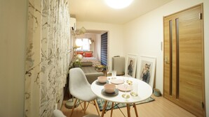 A dining area with a round table, chairs, and a ceiling light. There is a door and a radiator in the background. - Kikusui Mark's apartment (Sapporo)