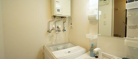 Une salle de bain avec un lavabo blanc, un miroir, un porte-serviettes et un radiateur fixé au mur.