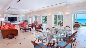 A spacious living room with a large glass dining table, comfortable seating, and a television. - Hemingway House by Blue Sky Luxury (Mullins)