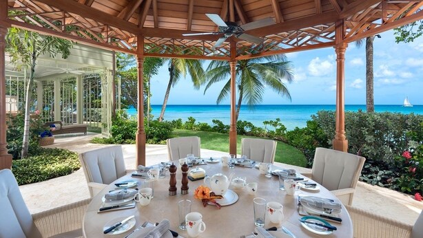 A round table set for a meal with white tablecloths, white chairs, and a view of the ocean. - Hemingway House by Blue Sky Luxury (Mullins)