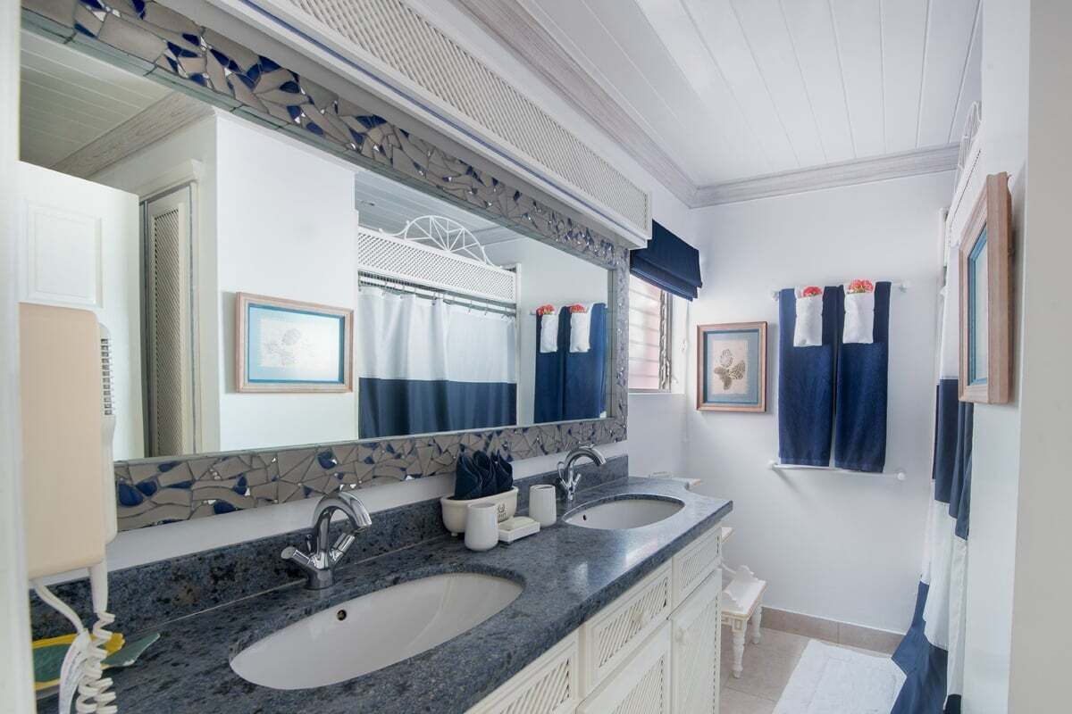 A bathroom with two sinks, a large mirror, and a tiled backsplash.