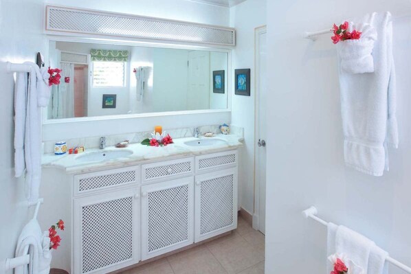A bathroom with two sinks, a large mirror, and white cabinetry.