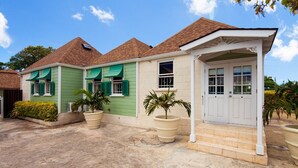 A two-story house with a front porch, green shutters, and a white door. - Arcadia by Blue Sky Luxury (Worthing)