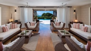 A spacious living room with two sofas, a coffee table, and a view of a pool and greenery. - Tom Tom by Blue Sky Luxury (Westmoreland)