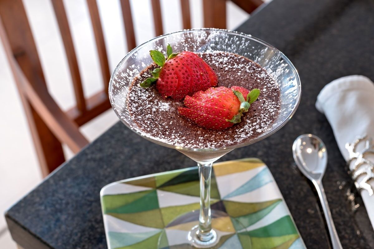 Een dessert in een glas op een tafel met een kleurrijke onderzetter.