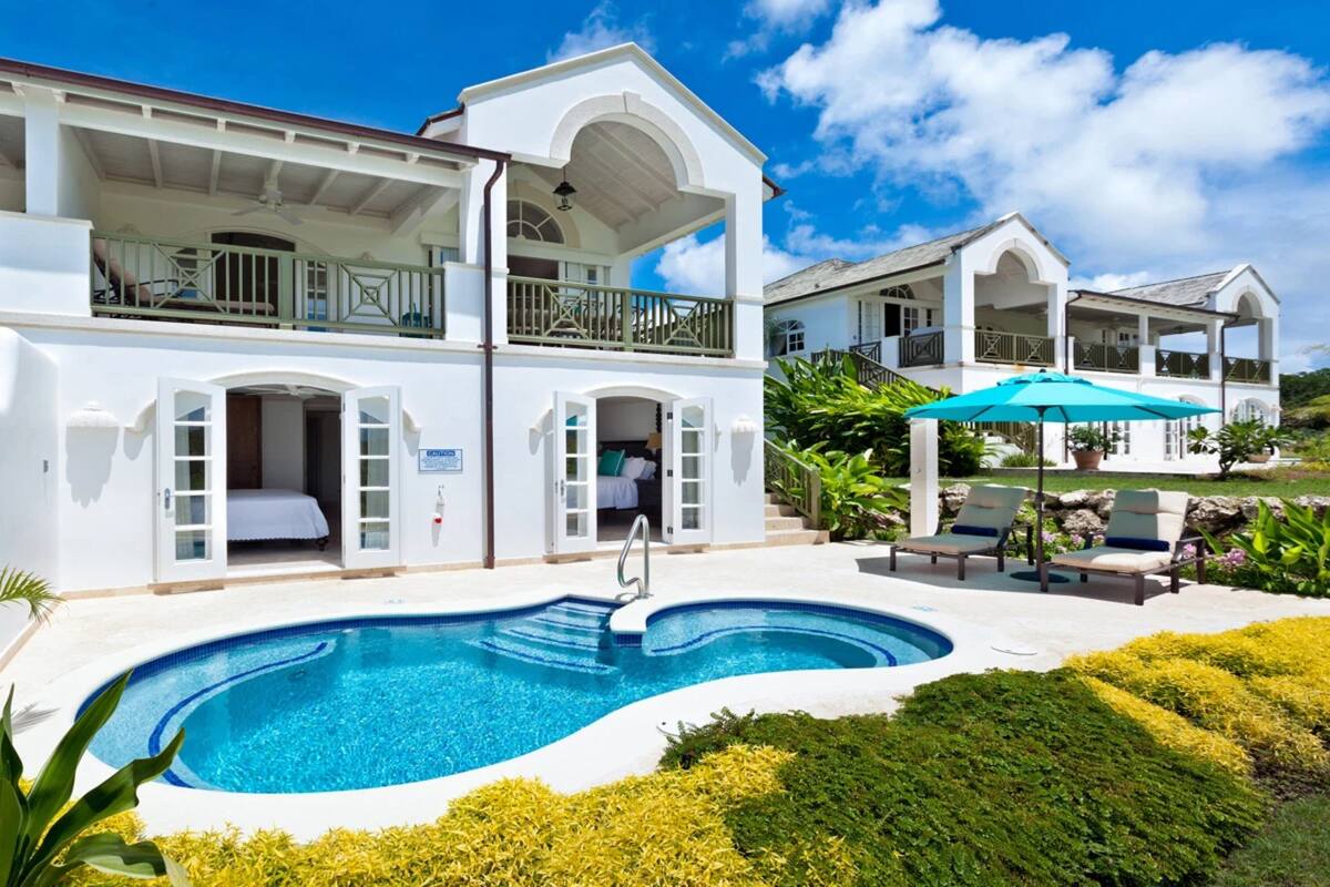Ein zweistöckiges, weißes Gebäude mit Pool, Außenbereich und überdachter Terrasse.