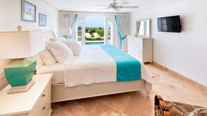 A bedroom with a bed, a ceiling fan, a TV, and a view of a swimming pool. - Royal Westmoreland - Sugar Cane Ridge by Blue Sky Luxury (Holetown)