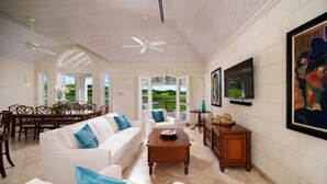 A spacious living room with a white sofa, a coffee table, and a dining area with wooden chairs. - Royal Westmoreland - Sugar Cane Ridge by Blue Sky Luxury (Holetown)