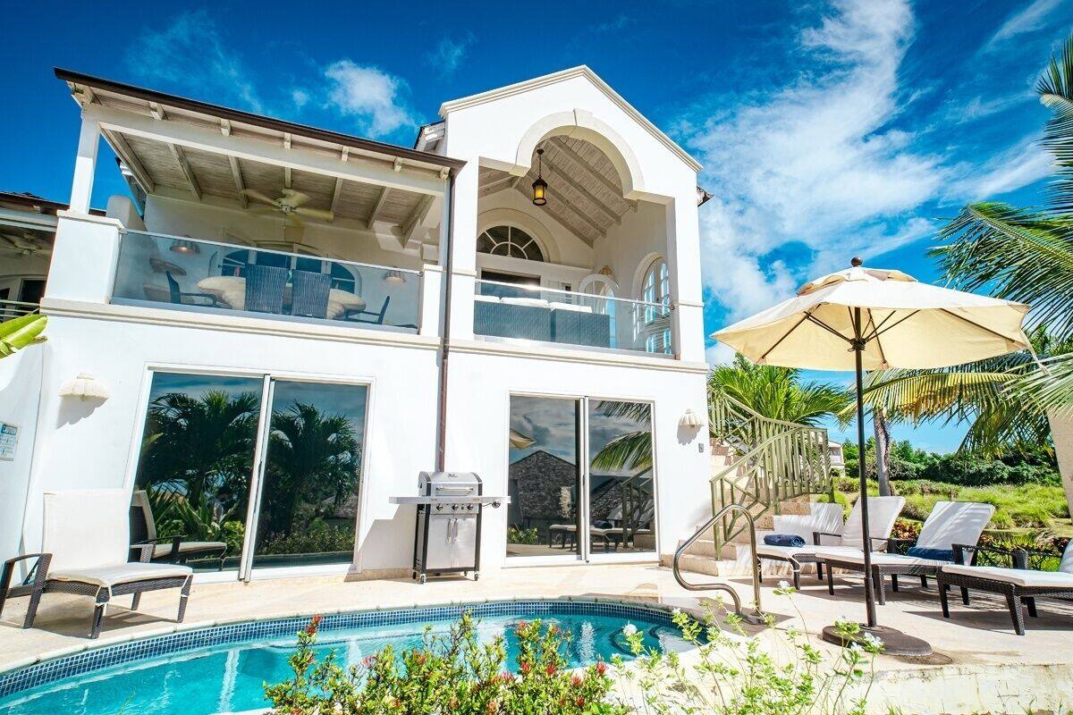 Ein zweistöckiges Haus mit Pool, Sitzgelegenheiten im Freien und Grill.