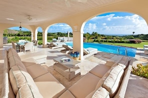 An outdoor lounge area with a pool, comfortable seating, and a view of the landscape.