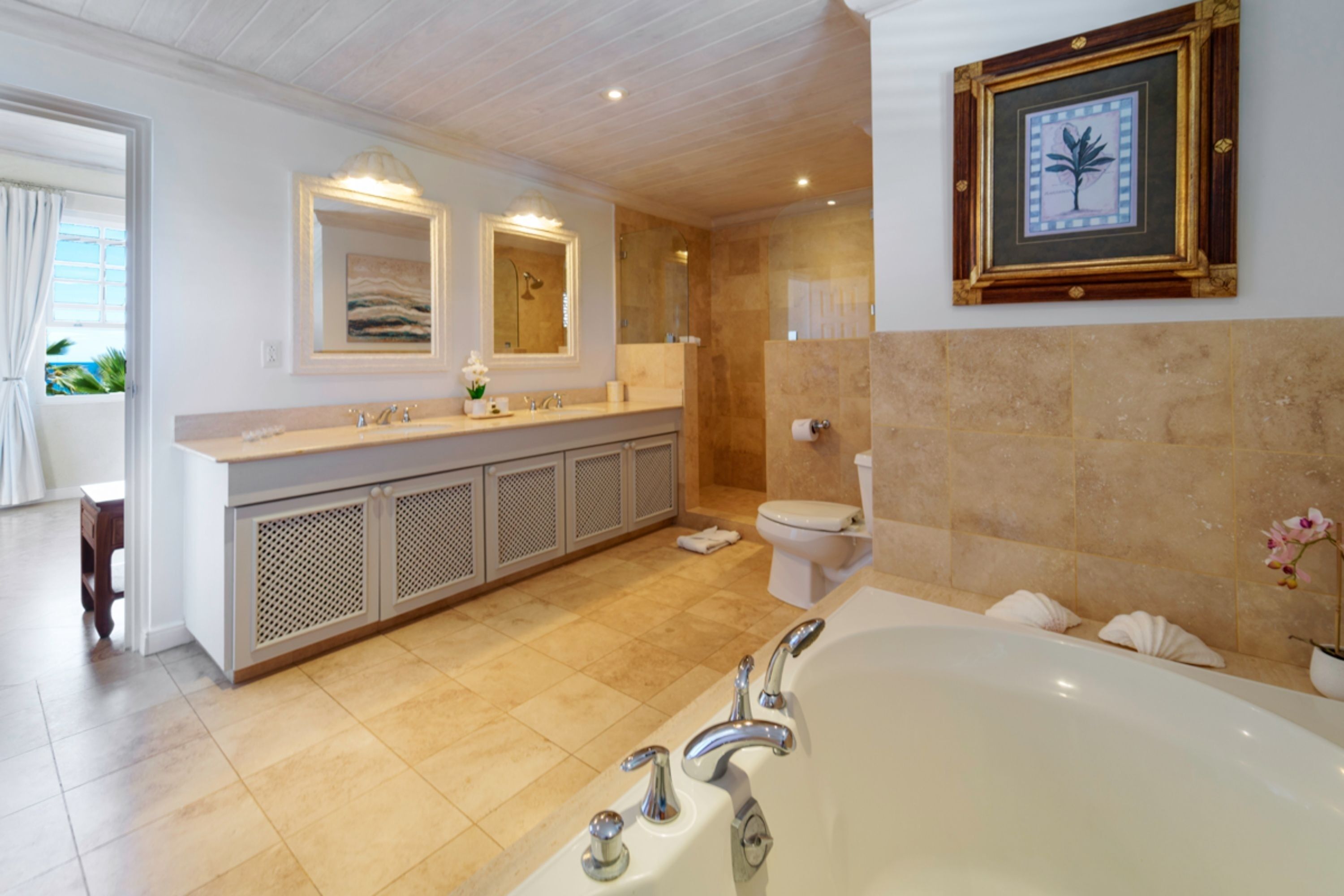 A modern bathroom with a large bathtub, a double vanity with two sinks, a toilet, and a shower area.