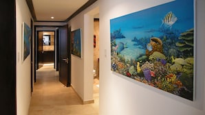 A hallway with a large underwater-themed painting on the right wall. - Coral Cove 3 - Green Flash Blue Sky Luxury (Paynes Bay)