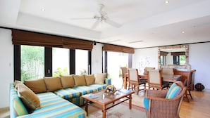 A spacious living area with a large sofa, a coffee table, and wicker chairs. - Coral Cove 3 - Green Flash Blue Sky Luxury (Paynes Bay)