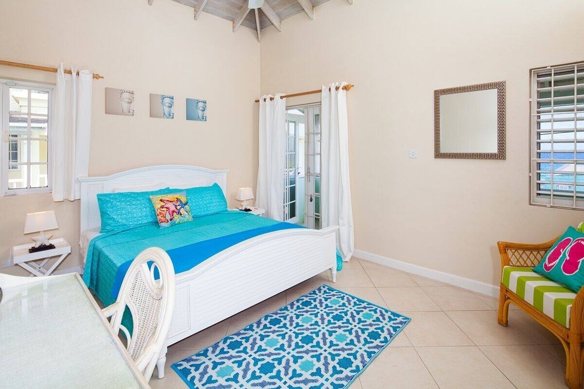 A bedroom with a bed, a chair, a table, and a window.