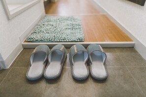 Un par de pantuflas a rayas sobre un suelo de baldosas, cerca de una alfombra.