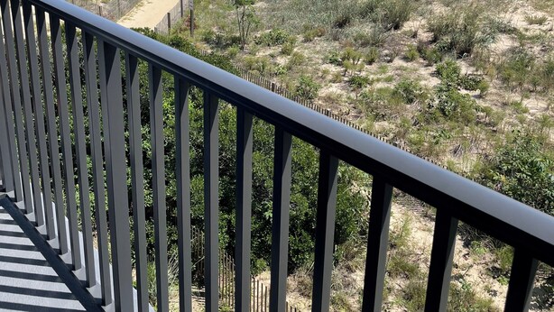 A beach view from a balcony with a railing, sandy beach, and ocean in the background. - Bimini 205 - Direct Oceanfront 87th St, WiFi, W/D, AC (Ocean City)
