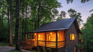 A log cabin with a porch, a staircase, and a door. - Spacious Log Cabin with Hot Tub, Fire Pit, Large Decks & Wood Fireplace (Logan)