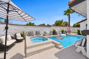 A pool area with lounge chairs, a hot tub, and a swan float.