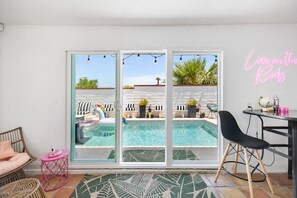 A modern living room with a pool, outdoor seating, and a neon sign. - Newly Upgraded Pool & Spa, Mountain Views, Gated La Quinta Cove Home, LIC#230224 (La Quinta)