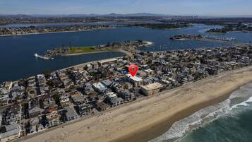 An aerial view of a coastal town with a beach, marina, and residential area.