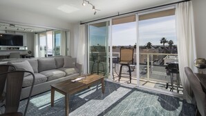 Un salon moderne avec un canapé, une table basse et une grande porte-fenêtre coulissante donnant sur un balcon extérieur.