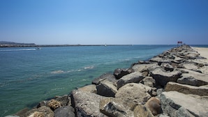 Un rivage rocheux offrant une vue dégagée sur l’océan et une jetée située au loin.
