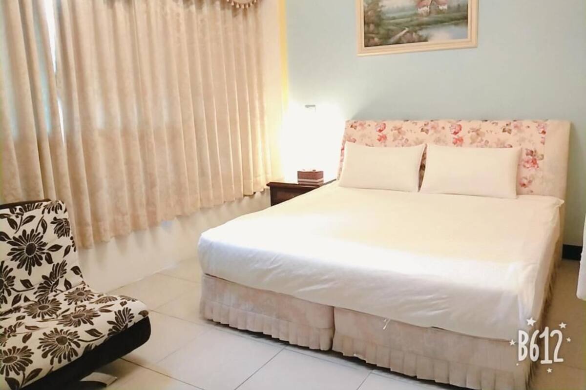 A bedroom with a bed, a chair, and a painting on the wall.