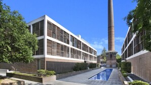 A courtyard with a modern building, a tall chimney, and a swimming pool. - Stylish Parkside Retreat - Outdoor Pool & Undercover Parking - Randwick (Randwick)