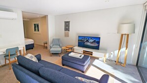 A modern living room with a sofa set, a TV, a desk, and a chair. - Stylish Parkside Retreat - Outdoor Pool & Undercover Parking - Randwick (Randwick)