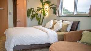 A bedroom with a bed, a sofa, a potted plant, and a window. - Coco Calm (Uruma)