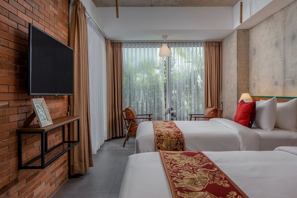A hotel room with two beds, a TV on the wall, a small table, and a chair.