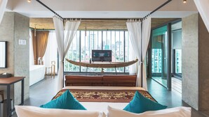 Ein modernes Hotelzimmer mit einem großen Bett, einer Holzbank, einem Fernseher und Blick auf die Stadt.