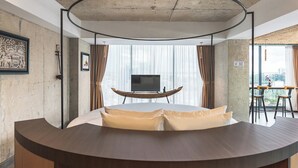 Ein modernes Zimmer mit einem bogenförmigen Bett, einem Fernseher auf einem Holzboden und Blick auf die Stadt durch große Fenster.