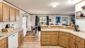 Une cuisine moderne avec des meubles en bois, un îlot central intégré et un coin repas offrant une vue agréable.