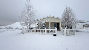 Une maison avec un porche abrité, une cour clôturée et des arbres couverts de neige.