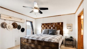 Une chambre à coucher avec une tête de lit en bois, un ventilateur de plafond et un porte-chapeaux fixé au mur.