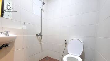 Ett litet, rent badrum med ett vitt handfat, en toalett och en dusch.