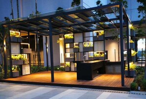 Enjoy cooking and dining al fresco in this outdoor kitchen with a central island, sink, and bar area.