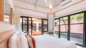 A spacious bedroom with a large bed, a view of the outside, and a sliding glass door leading to a patio area.