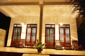 A lobby with a marble floor, wooden chairs, a potted plant, and a column. - Baby Elephant Green House (Udawalawa)