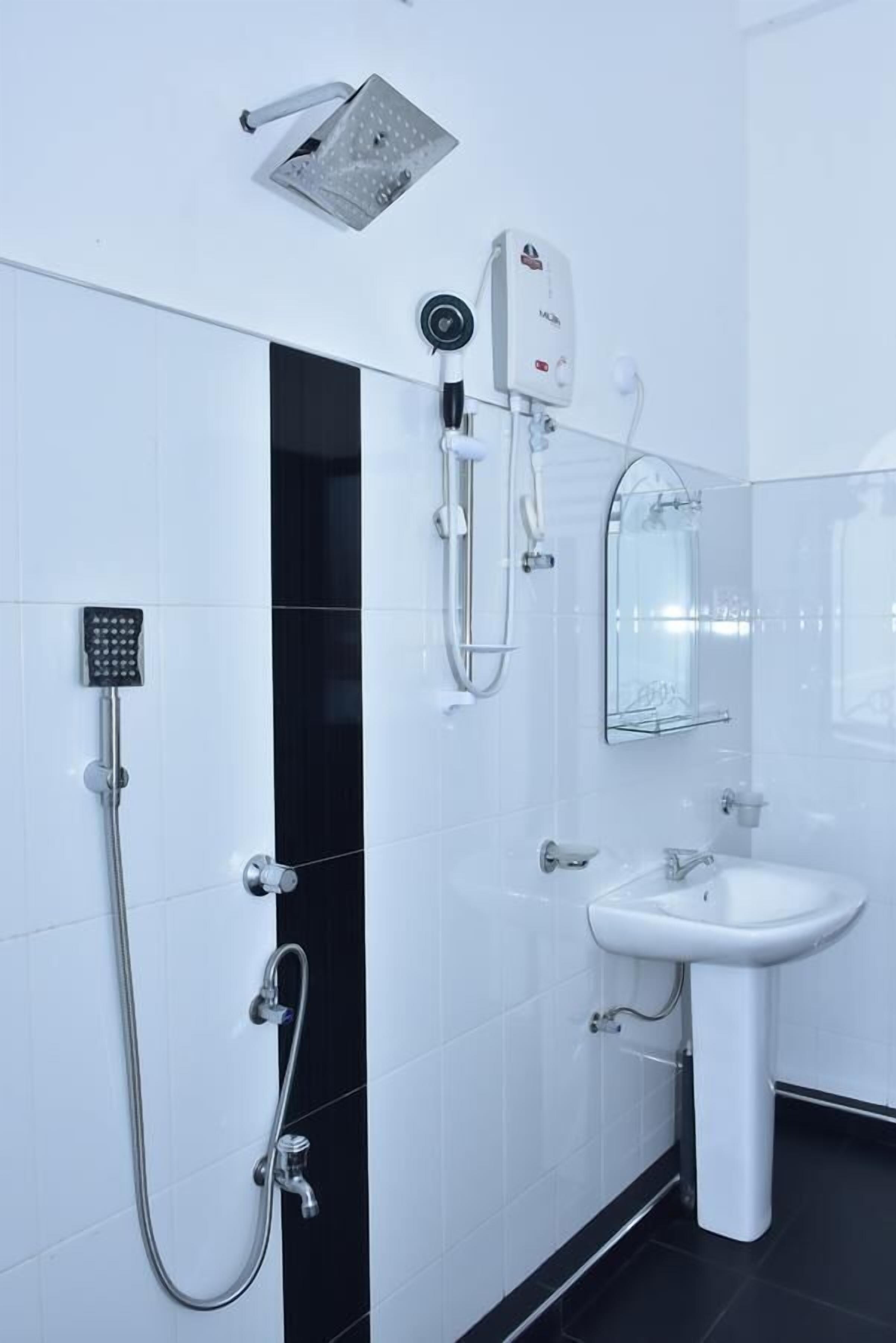 Une salle de bain moderne équipée d’une douche, d’un sèche-mains, d’un lavabo et d’un miroir.