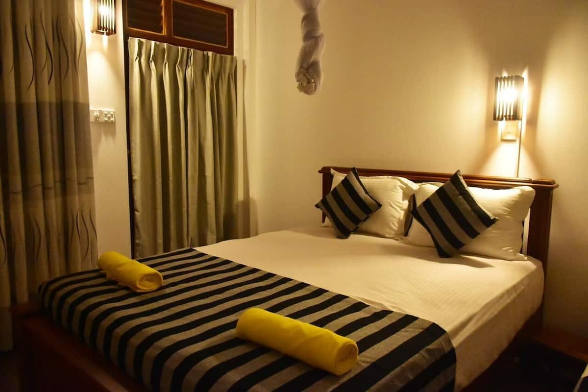 A hotel room with a bed, striped bedding, pillows, and a yellow towel.