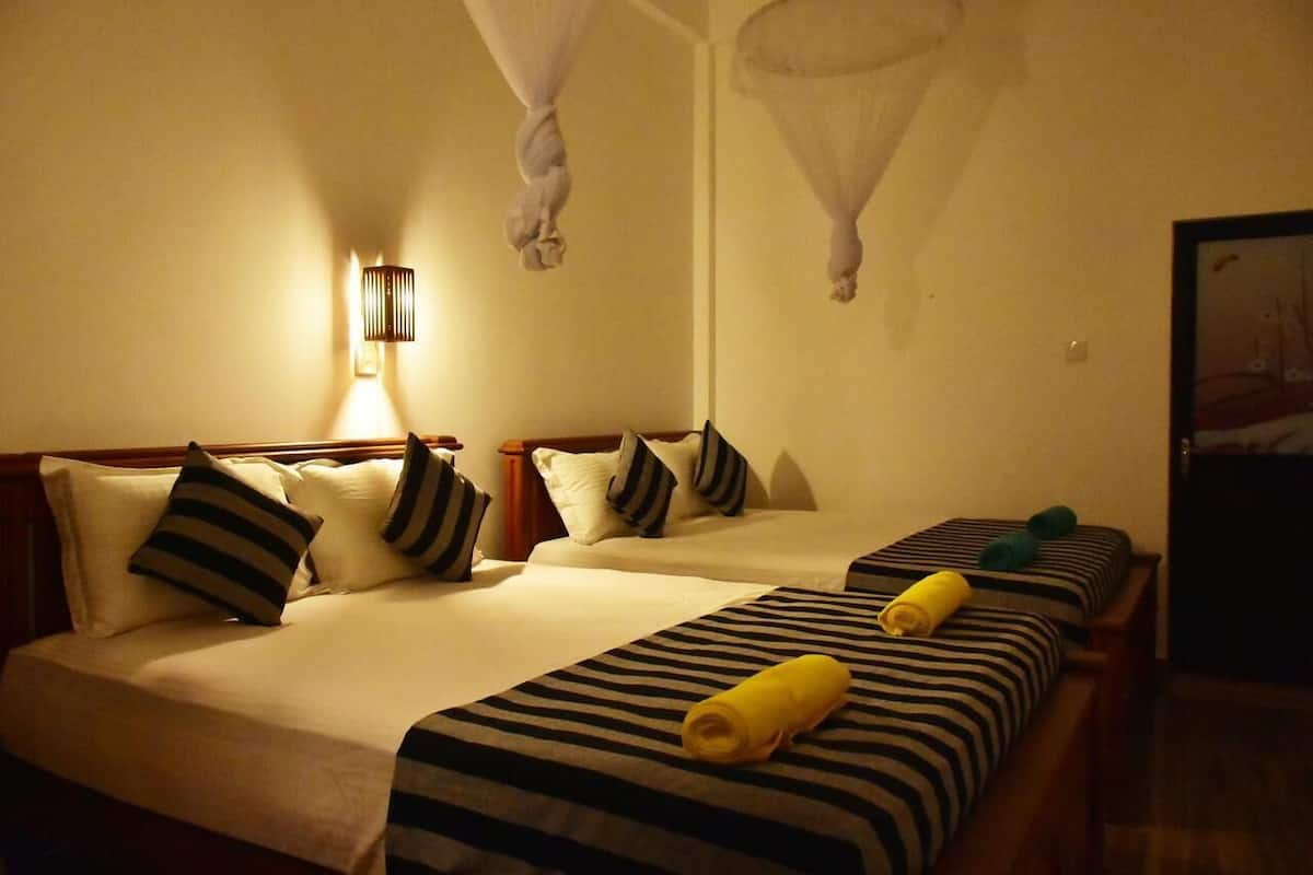 A hotel room with two beds, striped bedding, and a canopy bed.