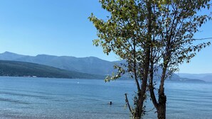 A lakeside view with a tree in the foreground, clear sky, and distant mountains. - Private suite! This house is the Iconic house of the Shuswap lake! (Blind Bay)