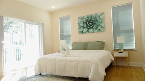 Una camera da letto con un letto grande, due comodini, un cuscino verde e un quadro appeso al muro.